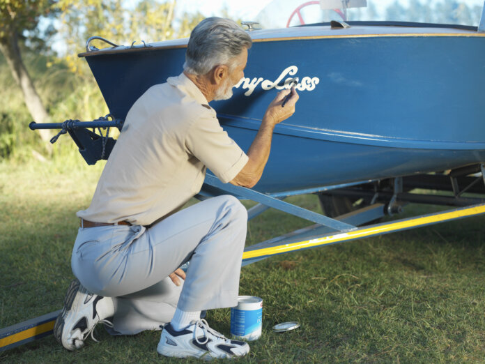 Ein Mann malt einen Name auf das Boot